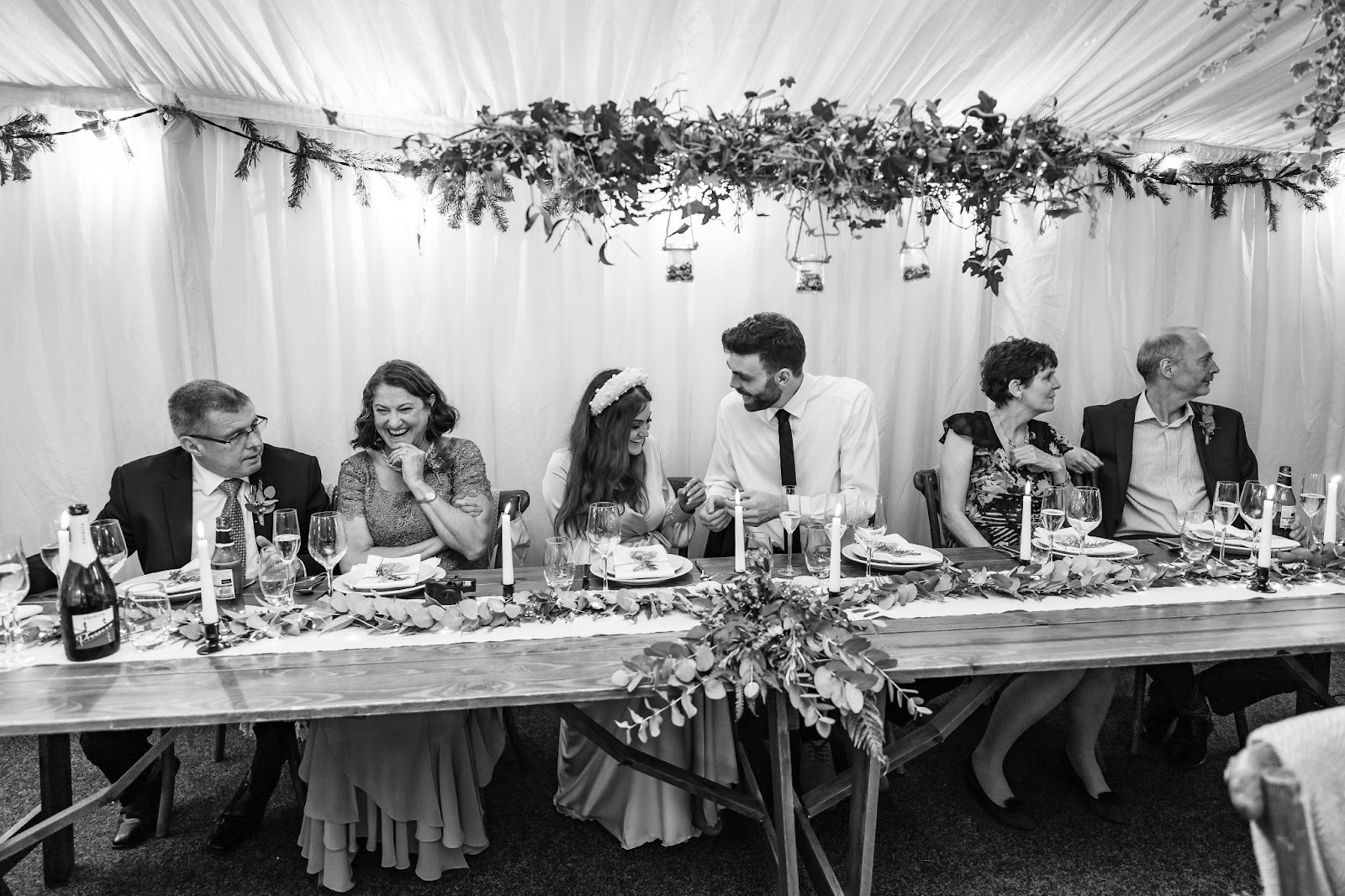 Bride and groom laughing with guests at reception table