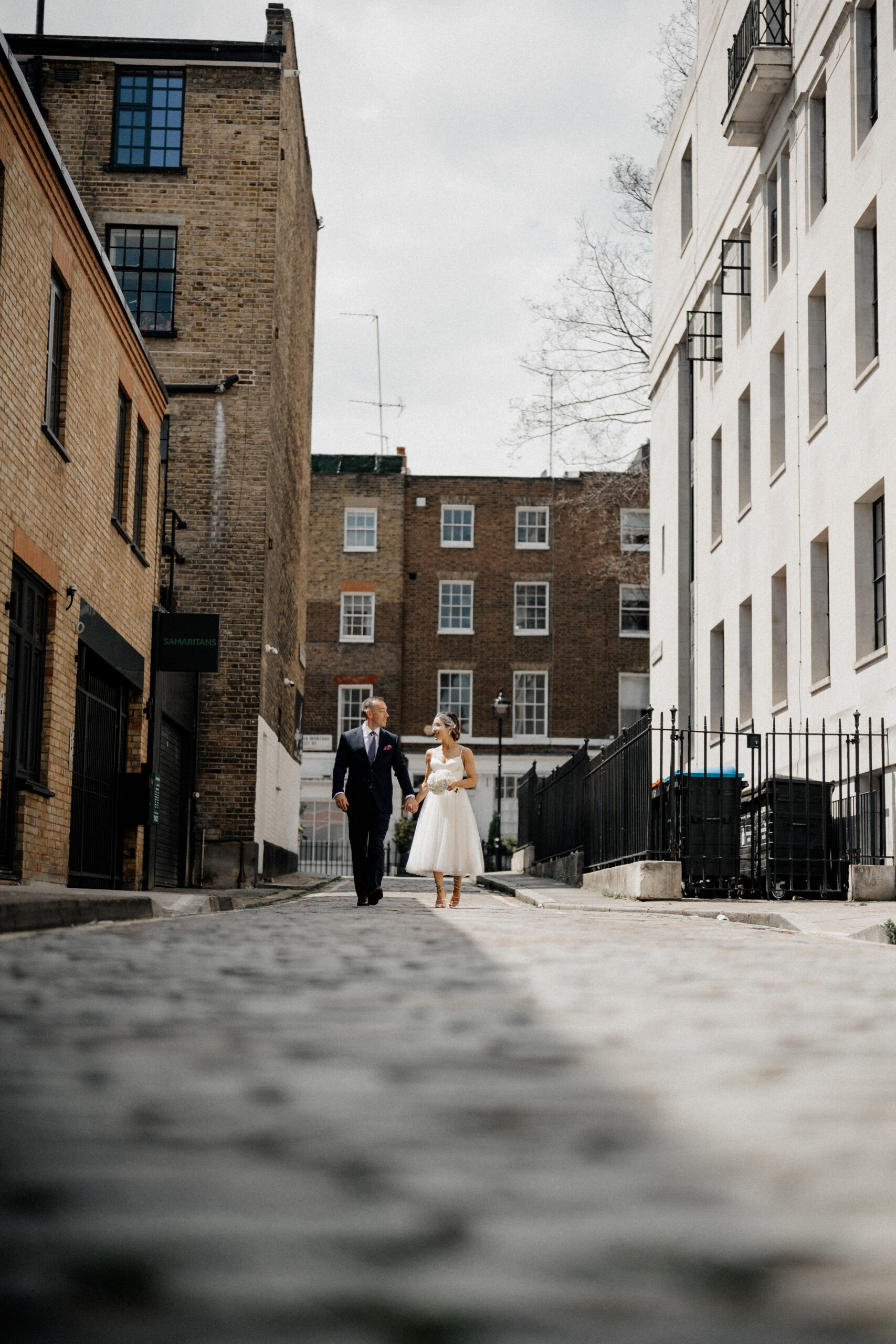 Couple walking on the cobblestone road after Marylebone Town Hall wedding