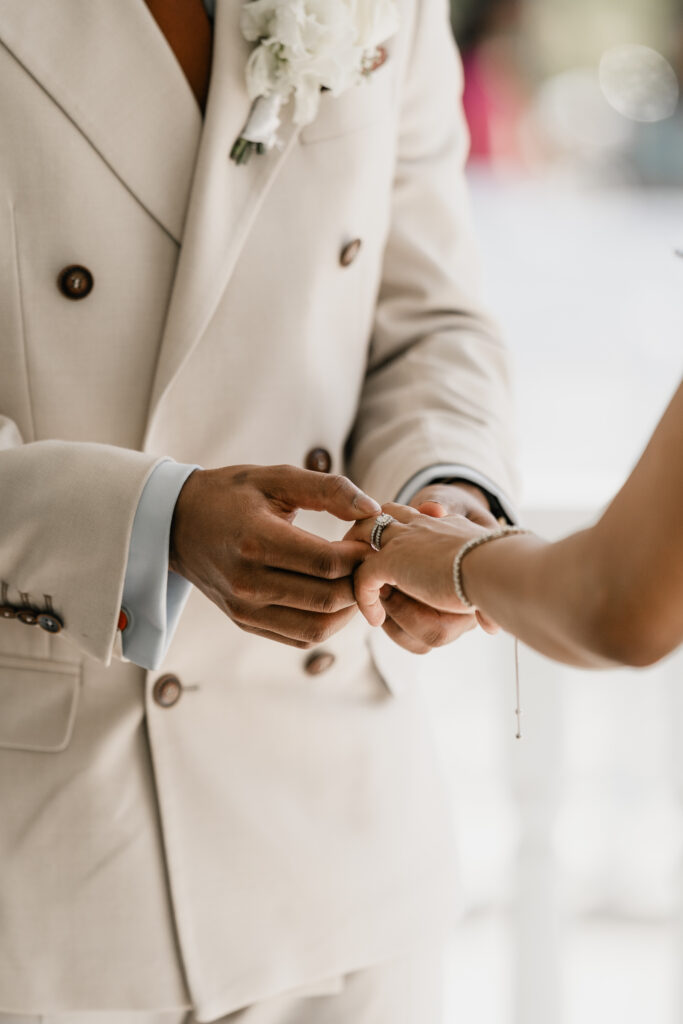 groom puts ring on bride's finger at morden park house