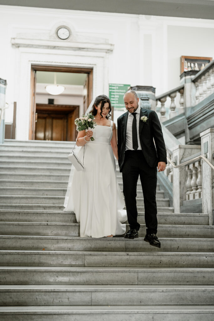 Newlyweds walking down steps outside Islington Town Hall London