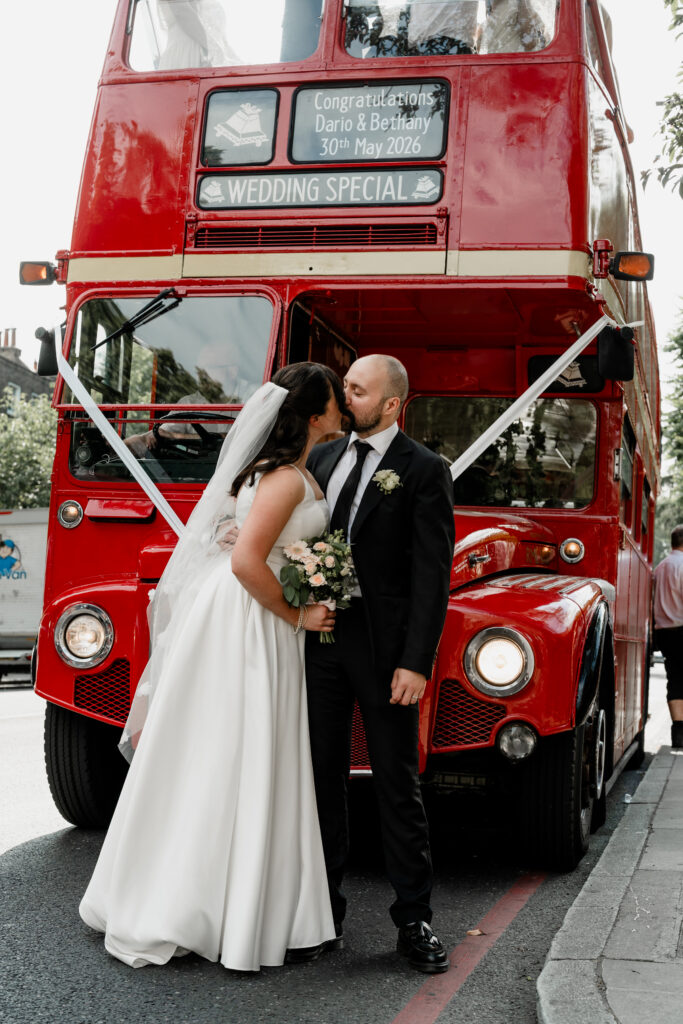 Bride and groom on wedding bus surrounded by cheering guests