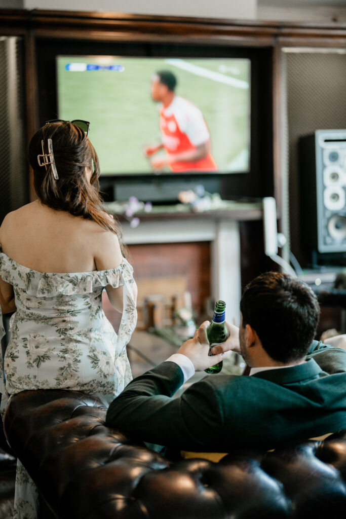 Guests reacting to football match during wedding reception celebration